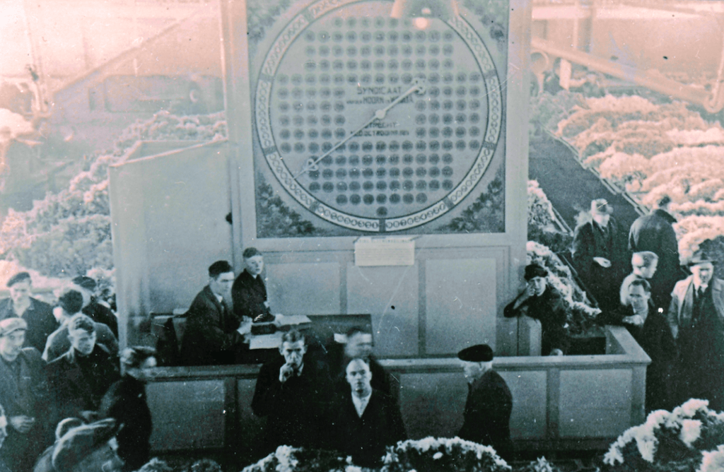 An auctioneer auctioning flowers underneath a mechanical clock